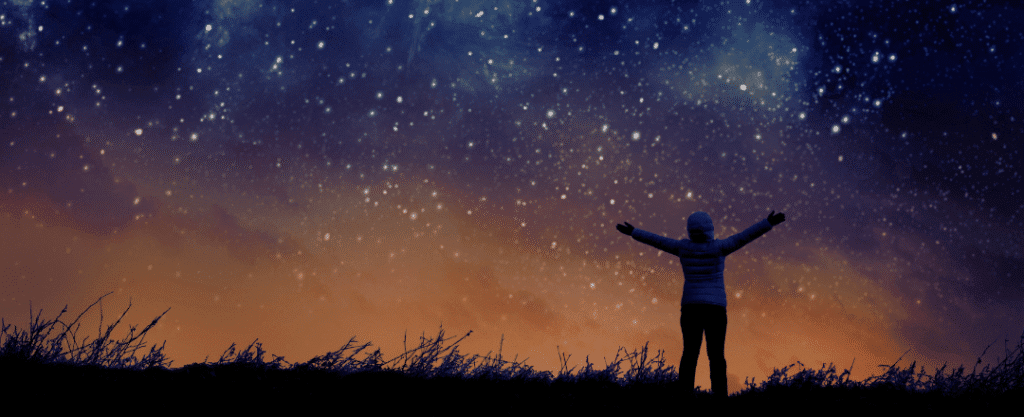 Mulher de braços abertos saudando as estrelas do céu noturno